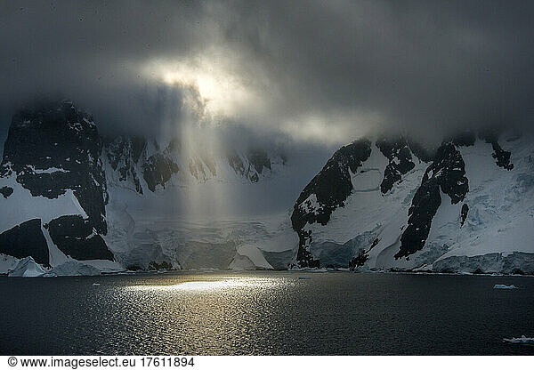 Early morning sun breaking through cloud cover in Antarctica's Lemaire Channel; Antarctica