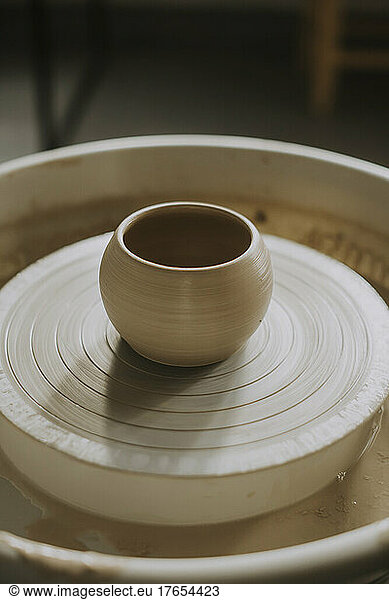 Earthen bowl on potter's wheel in workshop