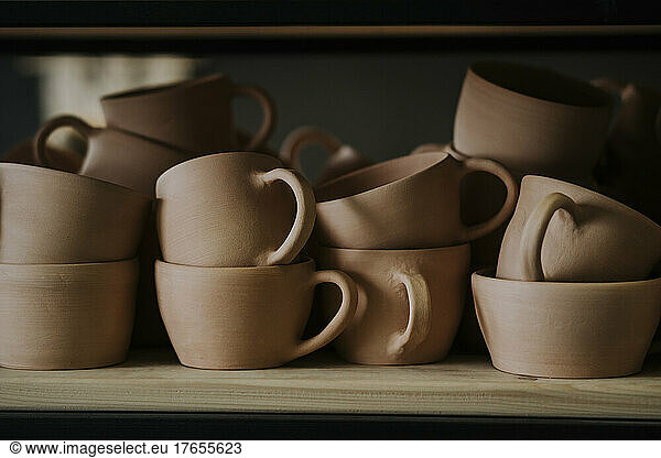 Earthenware cups on shelf in workshop