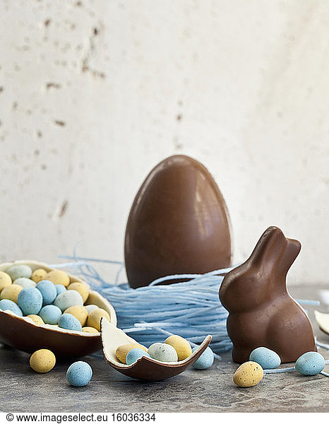 Easter chocolate egg in a blueberry candy nest  and a chocolate bunny  and a halved chocolate egg filled with mini chocolate eggs