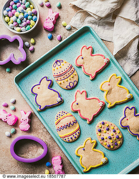 Easter cookies shaped like eggs and bunnies on green tray from above.