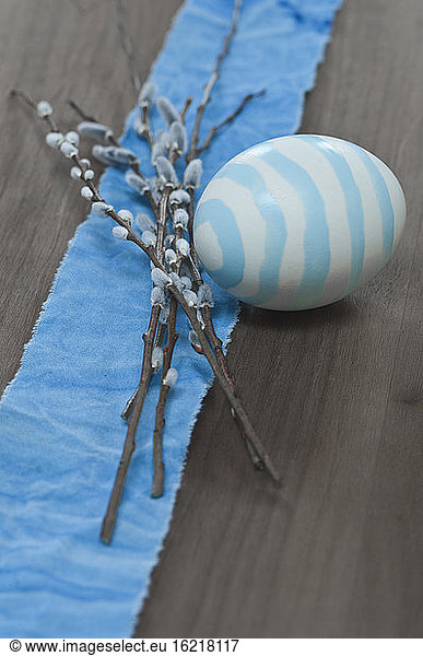 Easter eggs with pussy willow twigs on wooden surface