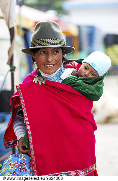 Ecuador  Young native woman with baby wearing red cape and hat