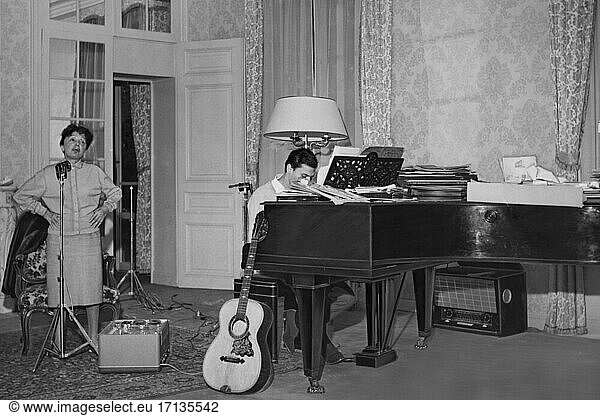 Edith Piaf  (Giovanna Gassion).
French Chansonsängerin  19.12.1915
Belleville – 11.10.1963 Paris. In Piaf’s apartment 67 bis boulevard Lannes  Paris:
She studies the chanson “Milord   while her lover Georges Moustaki accompanies her on the piano (he wrote the chanson text for her in 1959). Photo  end of August / beginning of September 1958.