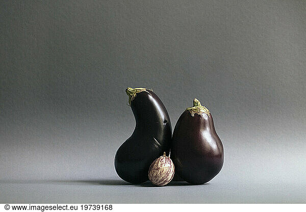 Eggplants and single gooseberry against gray background