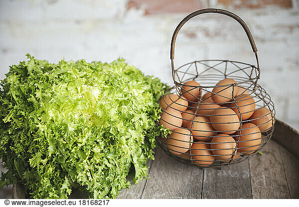 Eggs in basket by fresh green arugula