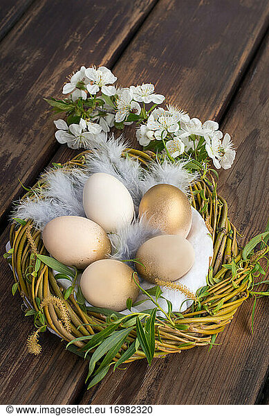 Eggs painted gold in the nest  on the wooden table to celebrate