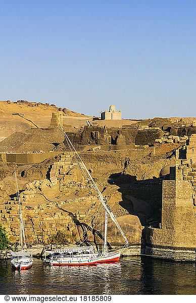 Egypt  Aswan Governorate  Aswan  Sailboats floating on bank of Nile river with Mausoleum of Aga Khan in background