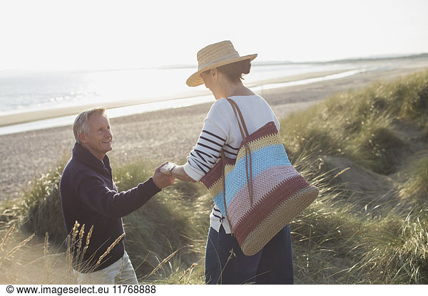 Ehemann hilft Frau auf sonnigem Strandgrasweg