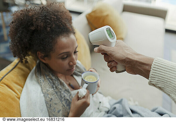 Ehemann nimmt Temperatur der kranken Frau mit Infrarot-Thermometer