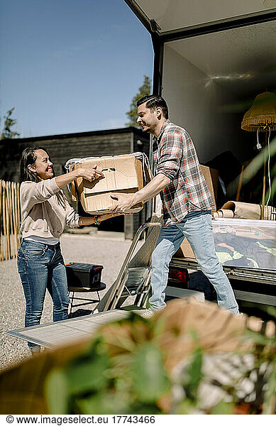 Ehepaar entlädt Kiste vom Lastwagen beim Umzug in ein neues Haus