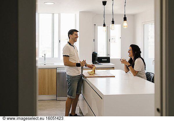 Ehepaar lacht beim Schneiden von Obst in der Küche zu Hause