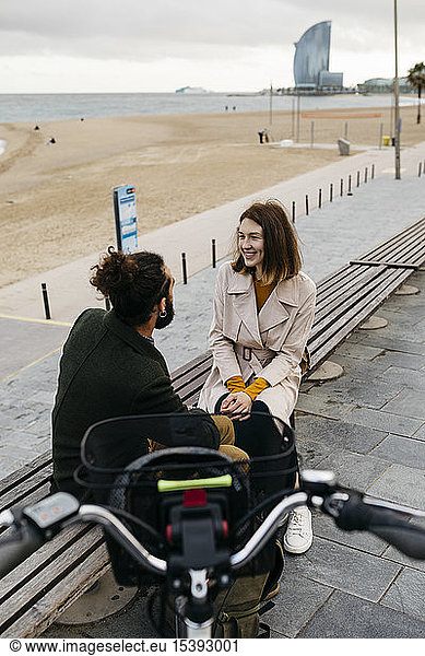 Ehepaar sitzt auf einer Bank an der Strandpromenade neben dem E-Bike und unterhält sich