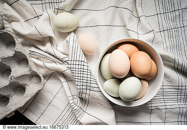 Eier in weißer Schale auf weißem und schwarzem Tischtuch mit Karton