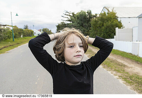 Eight year old boy  hands on his head  portrait