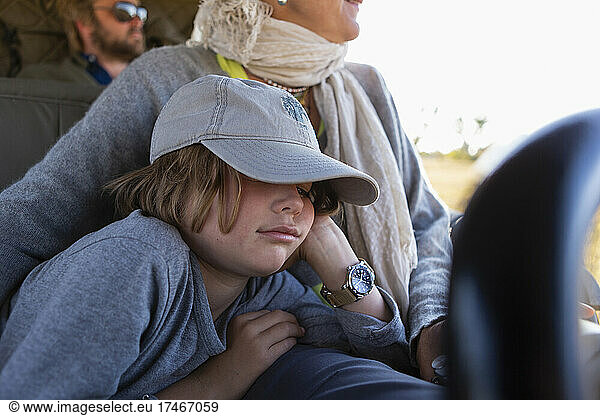 Eight year old boy in safari vehicle  sleeping beside his mother  in a safari jeep