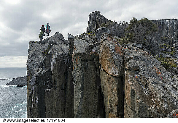 Ein Abenteurerpaar  bewaffnet mit Seilen und Kletterausrüstung  sucht seine nächste Herausforderung beim Klettern an den Meeresklippen von Cape Raoul  Tasmanien  Australien.