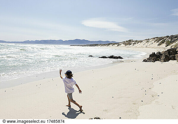 Ein achtjähriger Junge erkundet einen Sandstrand.