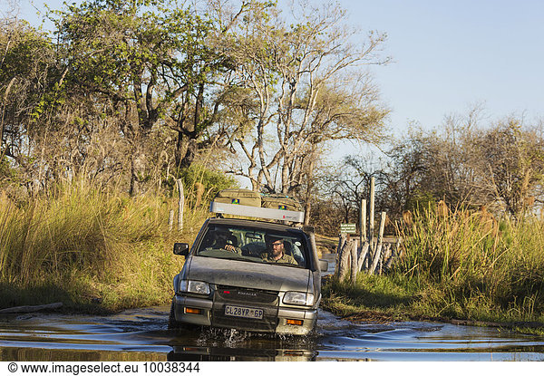Ein Allradfahrzeug durchquert einen Fluss  Straße im Okavango Delta führt über die Pfahlbrücke Third Bridge  Moremi Wildreservat  Botswana  Afrika