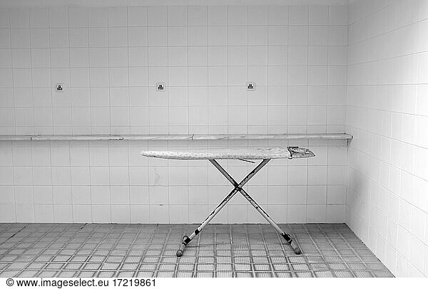 Ein altes Bügelbrett steht in einem leeren Raum mit gefliesten Wänden
