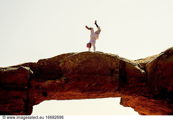 Ein Beduine macht einen Handstand auf einem Felsbogen in Wadi Rum  Jordanien