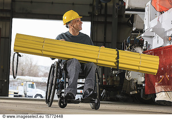 Ein behinderter Arbeiter transportiert Material in einer Werkstatt