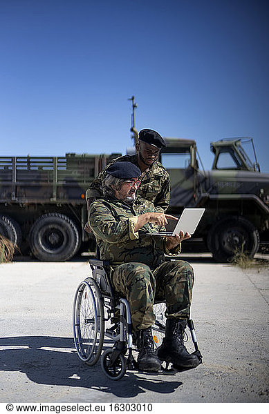 Ein behinderter Militäroffizier arbeitet an einem Laptop mit einem Kollegen an einem sonnigen Tag