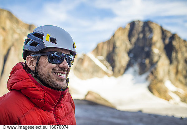 Ein Bergsteiger lächelt  während er die freie Natur genießt.
