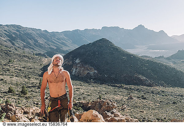 Ein Bergsteiger ohne Hemd steht auf einem Felsen mit dem Berg im Hintergrund