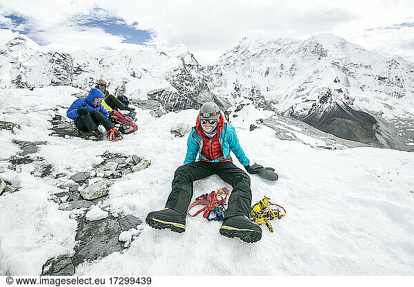 Ein Bergsteiger sitzt erschöpft nach einem erfolgreichen Gipfel auf dem Island Peak