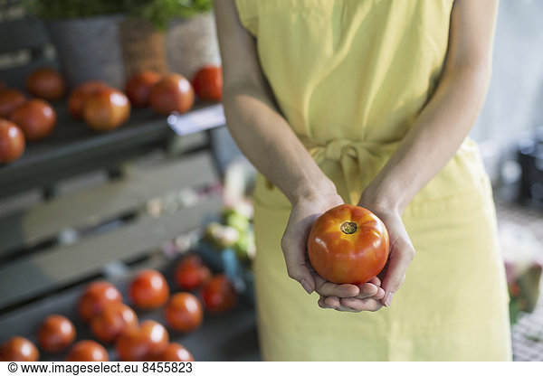 Ein biologischer Obst- und Gemüsebetrieb. Eine Frau  die eine Tomate hält.