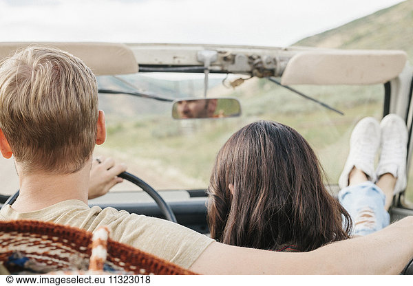 Ein Ehepaar auf einer Autofahrt in den Bergen  sitzend in einem offenen Jeep mit offenem Dach.