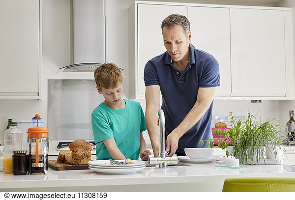 Ein Familienhaus. Ein Mann und ein Junge beim Aufräumen und Abwaschen.