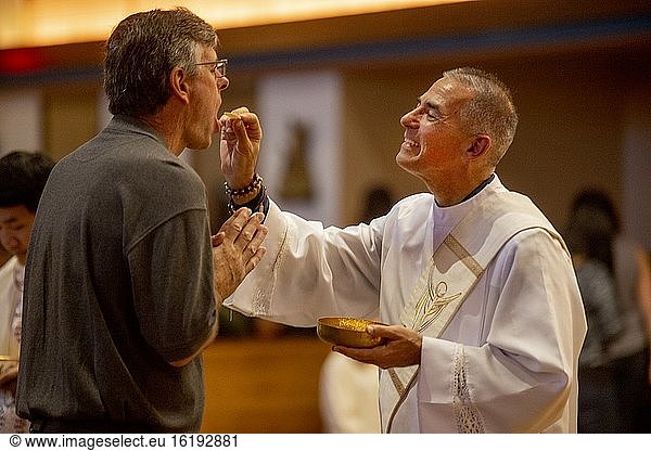 Ein gewandeter Diakon reicht einem Gläubigen während der Messe in einer katholischen Kirche in Tustin  Kalifornien  eine Hostie.