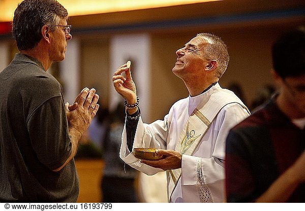 Ein gewandeter Diakon reicht einem Gläubigen während der Messe in einer katholischen Kirche in Tustin  Kalifornien  eine Hostie.