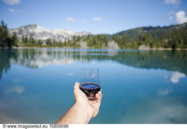 Ein Glas Rotwein am Bergsee geniessen.