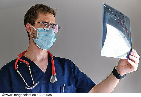 ein gut aussehender Arzt  der ein Röntgenbild betrachtet