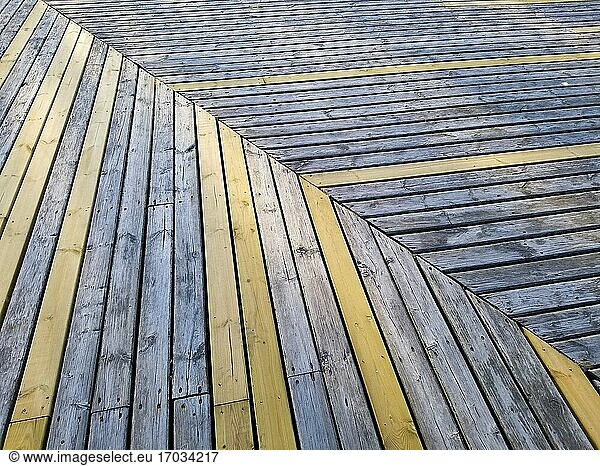 Ein Holzboden aus gelben und blauen Dielen. Dielenmuster in einem Winkel.