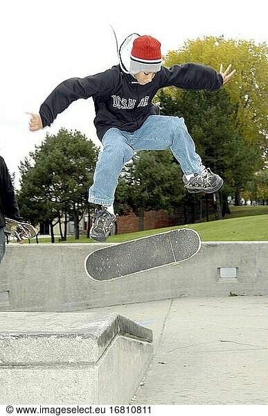 Ein Jugendlicher führt in einem öffentlichen Park Manöver auf einem Skateboard durch.