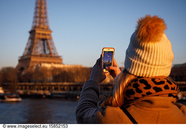 Ein junger Erwachsener macht ein iPhone-Foto vom Eiffelturm in Paris.