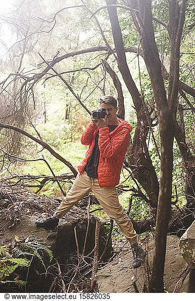 Ein junger Mann fotografiert in einem Regenwald