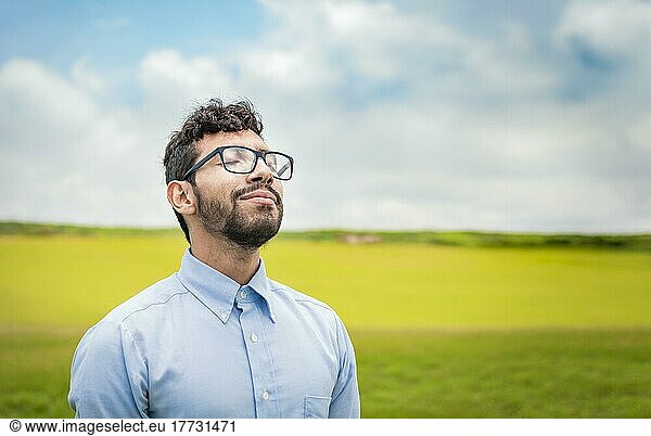 Ein junger Mensch atmet frische Luft auf einem Feld  Ein Mann atmet frische Luft auf einem Feld  Ein glücklicher Mann atmet frische Luft auf einer Wiese