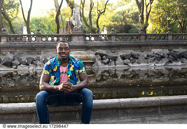 Ein junger schwarzer Mann im Park. Porträt eines Reisenden im Freien. Porträt