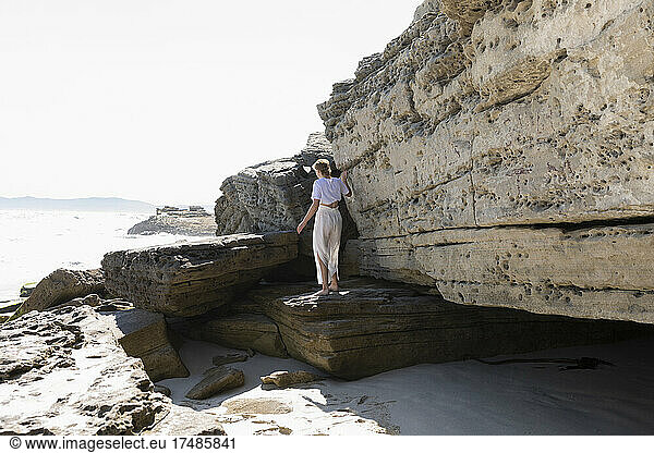 Ein junges Mädchen erkundet die Klippen und Felsen an einem Strand an der Atlantikküste.
