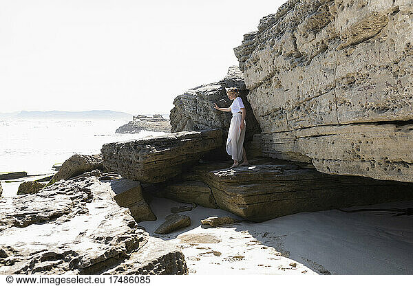 Ein junges Mädchen erkundet die Klippen und Felsen an einem Strand an der Atlantikküste.