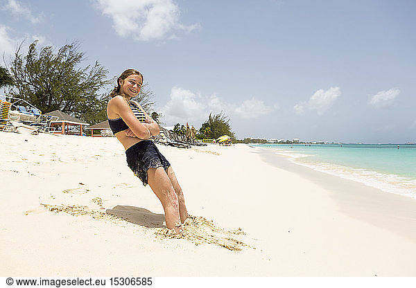 Ein junges Mädchen lehnt im Sand