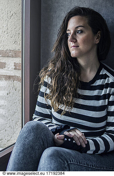 Ein junges Mädchen sitzt am Fenster und ruht sich aus