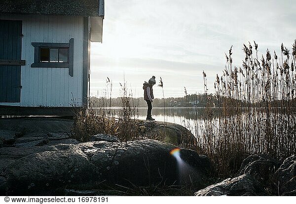ein junges Mädchen stand auf den Felsen neben einer traditionellen schwedischen Hütte