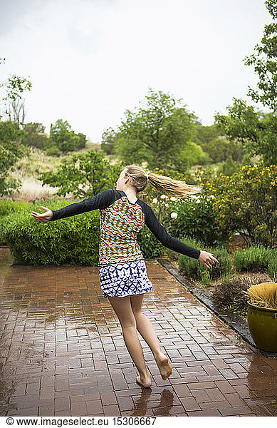 Ein junges Mädchen tanzt im Regen