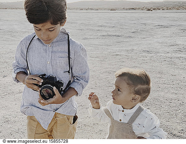 Ein Kind hält eine Kamera und ein jüngeres Kind steht neben mir
